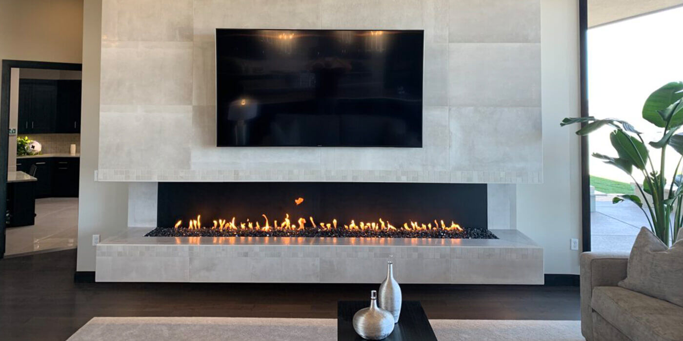 An extra-large linear gas fireplace stretching across a wall in an upscale home with a flatscreen TV mounted above