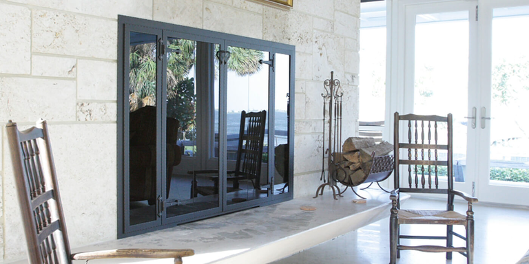 A modern glass door with a black frame installed on a masonry fireplace