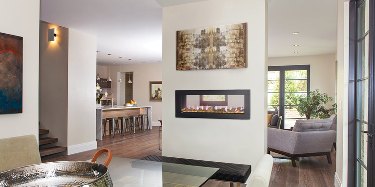 A linear see-through fireplace separating a living space and dining area