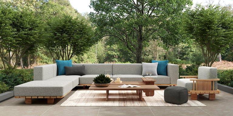 A contemporary outdoor space with an armless sectional and wooden tables. 
