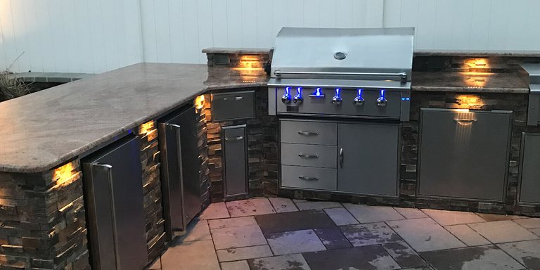 A large L-shaped outdoor kitchen island with stainless steel components