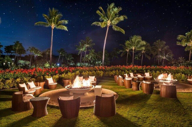 Gas fire pits surrounded by chairs at a Hawaiian resort at night