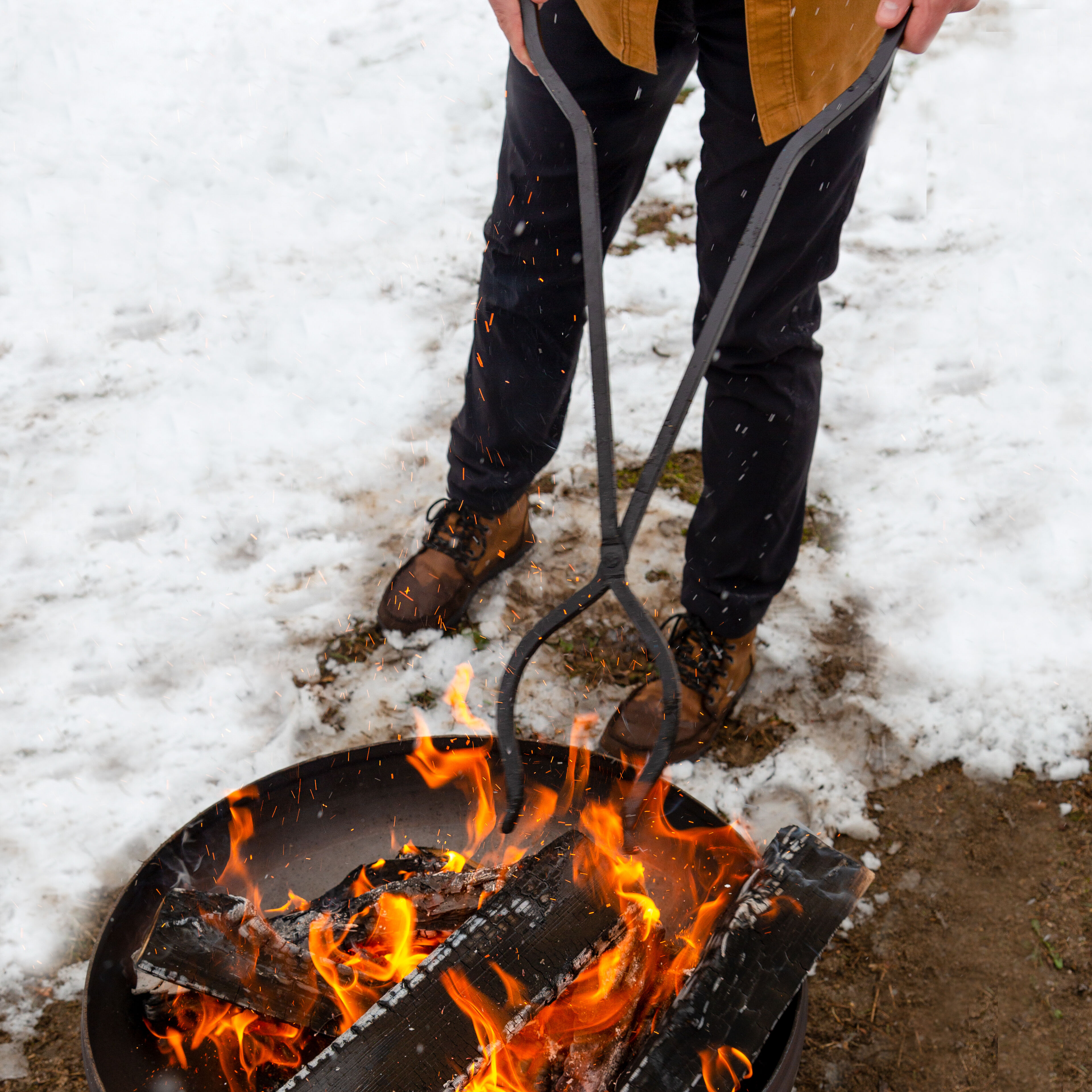 Man holding steel fire pit tongs over Patriot Fire Bowl