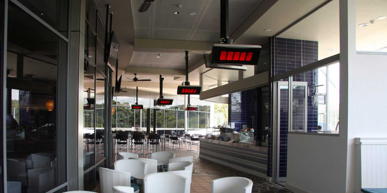 An outdoor lounge space with several Bromic Platinum Natural Gas patio heaters installed on the ceiling 