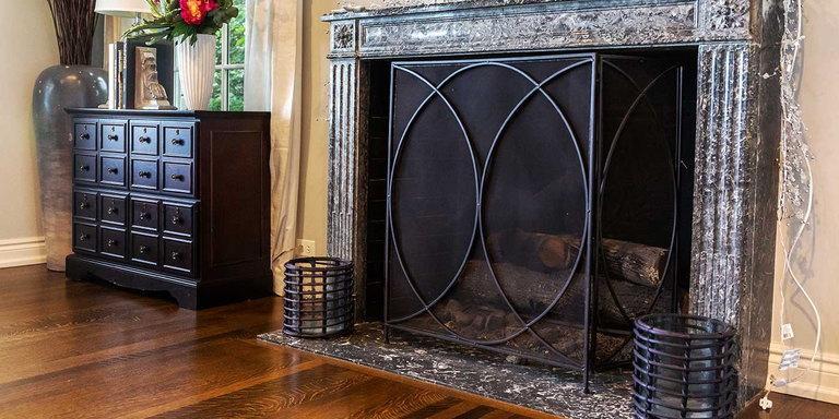 A traditional wood burning fireplace with a decorative black screen