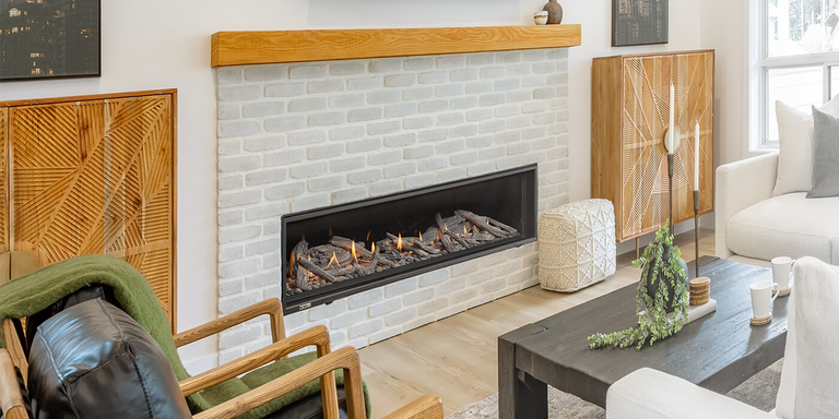 A modern hearth with light colored bricks, a wooden mantel, and a linear gas fireplace