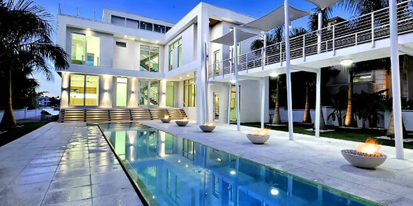 Gas fire bowls along a swimming pool in an ultramodern luxury outdoor patio