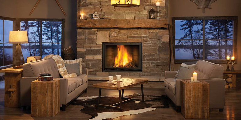 A rustic living room with a natural stone hearth and chimney and a square wood burning fireplace.