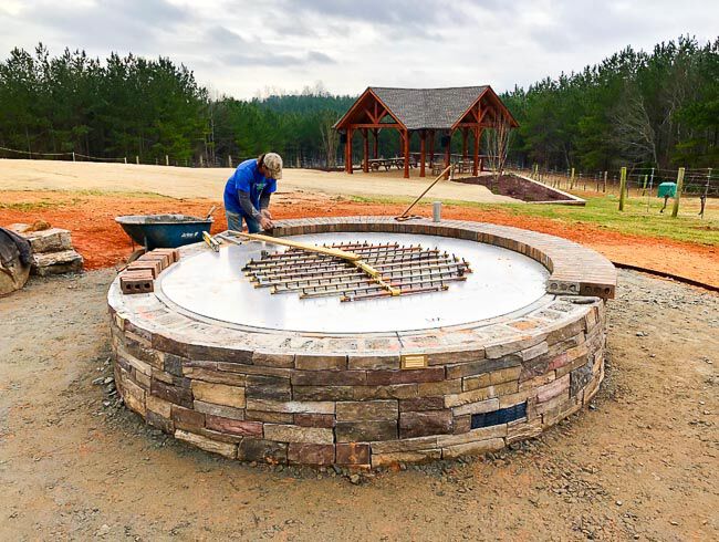 Worker installing a burner into a larege masonry fire pit