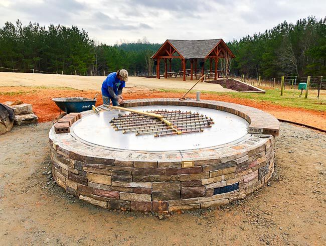 Worker installing a burner into a larege masonry fire pit