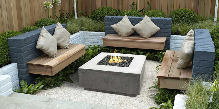 An outdoor lounge space with built-in benches and a medium-sizes, concrete gas fire pit in the center