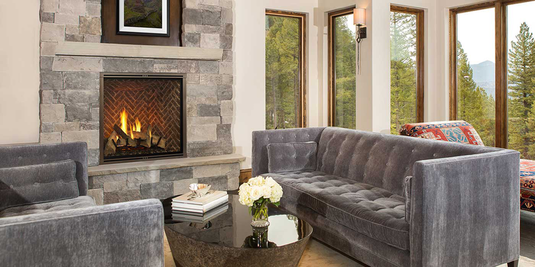 A traditional home with a natural stone hearth and a classic, square gas fireplace with a realistic gas log set