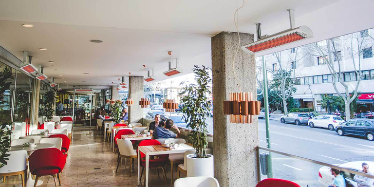 A close-up view of a ceiling-mounted, stainless steel electric patio heater with soothing, orange heating elements.