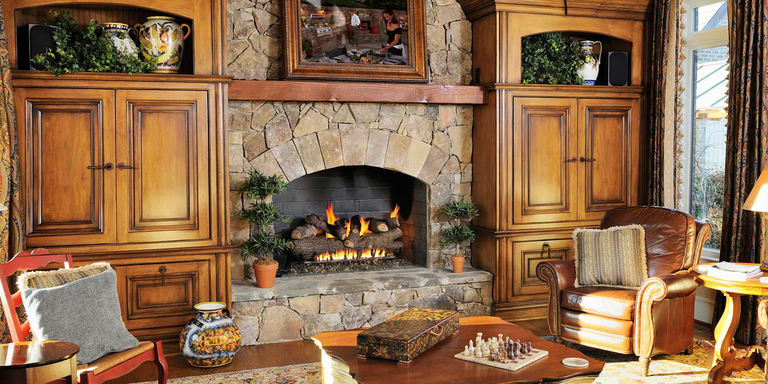 A traditional living space with an natural stone hearth, arched fireplace, and rustic gas log set.