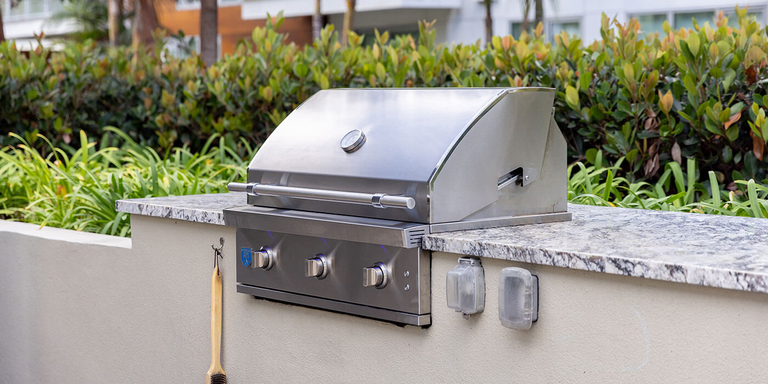 PGS stainless steel grills can be built into any custom kitchen island, like this stucco and granite island with a space for the grill head and built-in hooks for your cooking utensils. 