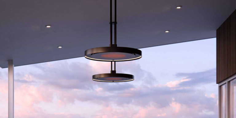 The Bromic Eclipse Smart-Heat Pendant Electric Patio Heater installed in an enclosed patio space underneath a large white dining table with eight chairs.