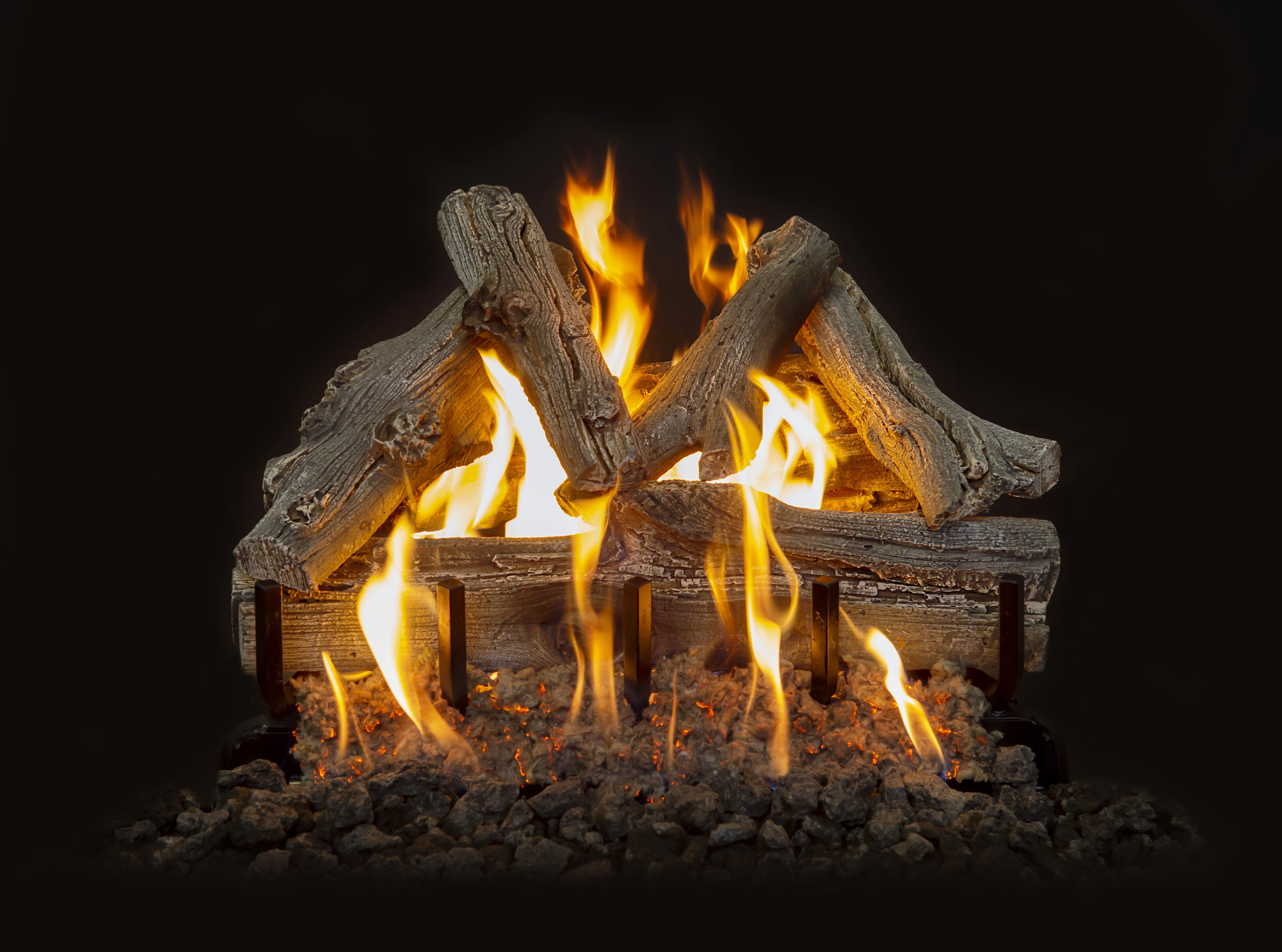 A Vented gas log set with a rustic, detailed brown-gray bark finish, black lava rock in the media bed, and yellow flames.