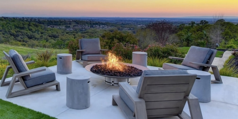 An outdoor seating area with a stainless steel gas fire pit in the center