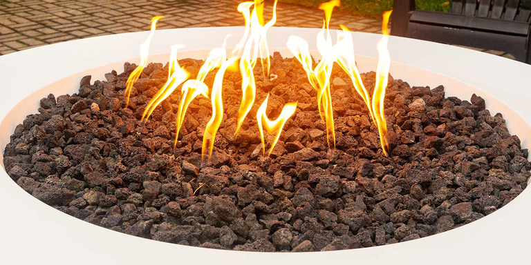 A gas fire pit with black lava rock media