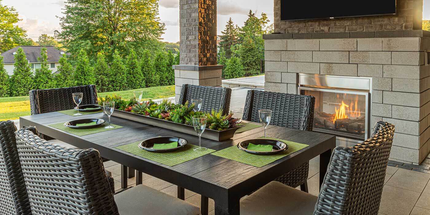 An outdoor patio space with a dining table and a contemporary, outdoor gas fireplace.