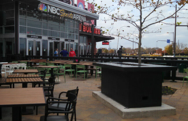 A large black fire pit table on the outdoor patio of the NBC Sports Arena