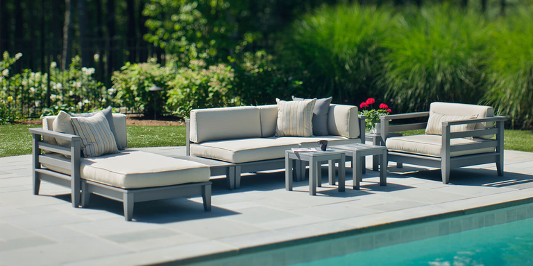 A patio furniture set near a pool, complete with a chaise lounge, a sofa, and an armchair.