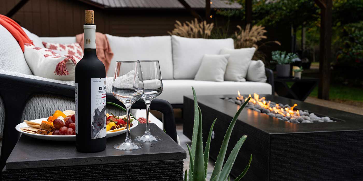 An outdoor living space with wine and snacks, an outdoor seating area, and the Zen Gas Fire Pit by FlameCraft