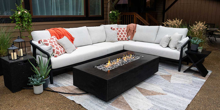 A contemporary outdoor living space with a white sectional couch and the Zen Gas Fire Pit by FlameCraft