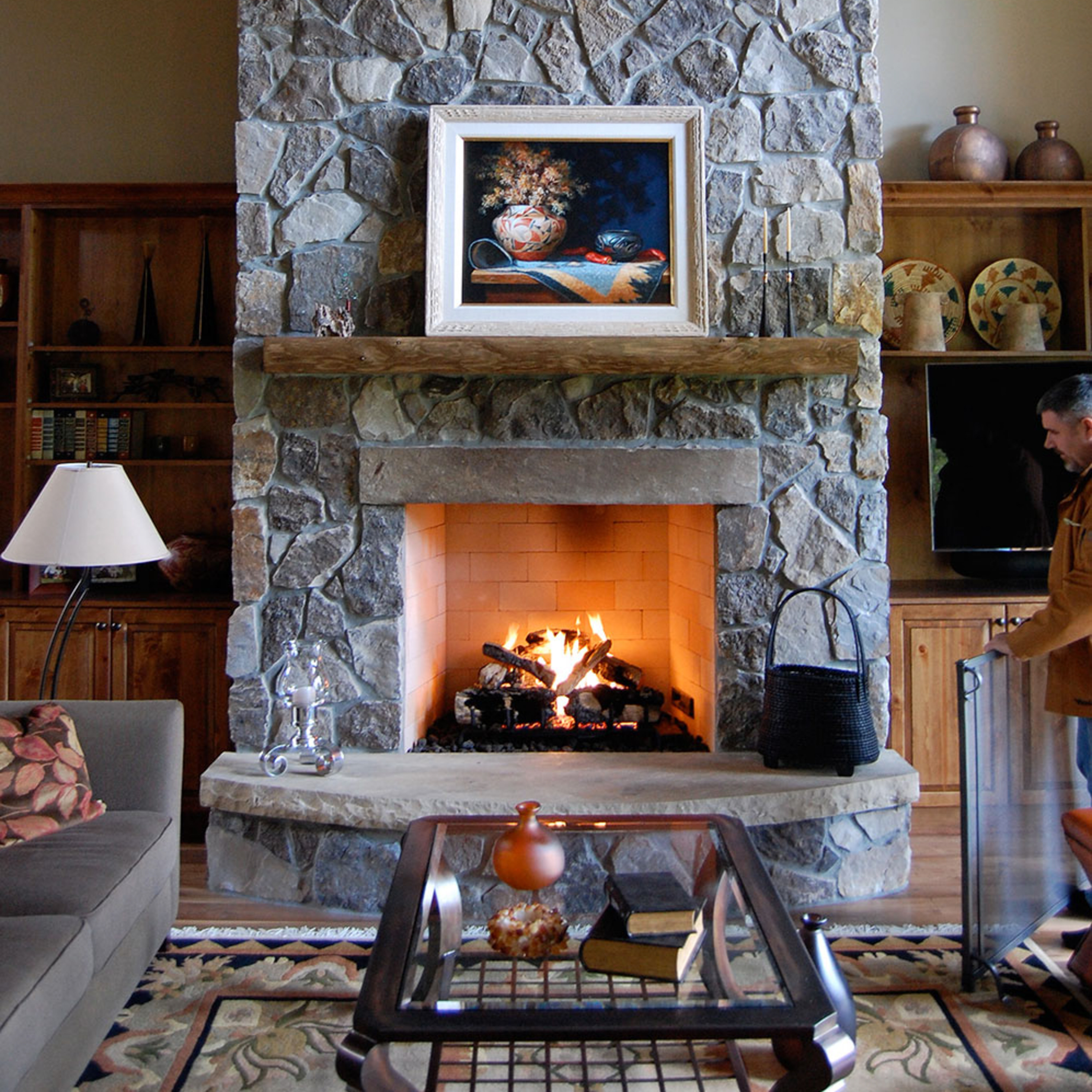 The Isokern B-Vetto Gas Fireplace installed on a rustic, stone hearth with a wooden mantel and traditional-style decor.