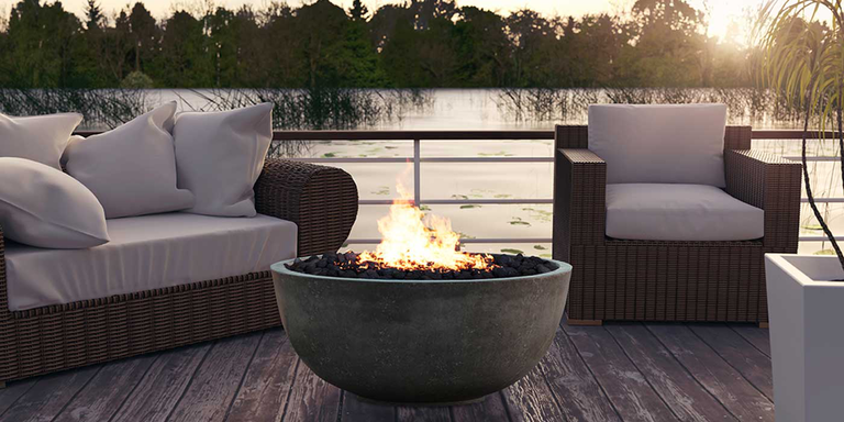 A concrete gas fire bowl installed on an outdoor deck off of a lake