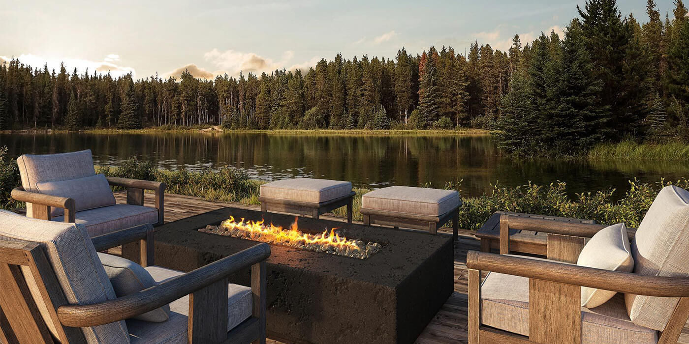A linear gas fire pit installed on an outdoor deck overlooking a lake A linear gas fire pit installed on an outdoor deck overlooking a lake