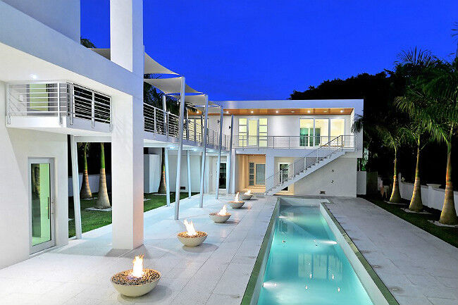 Outdoor patio with a swimming pool and five gas fire bowls at an ultramodern luxury home