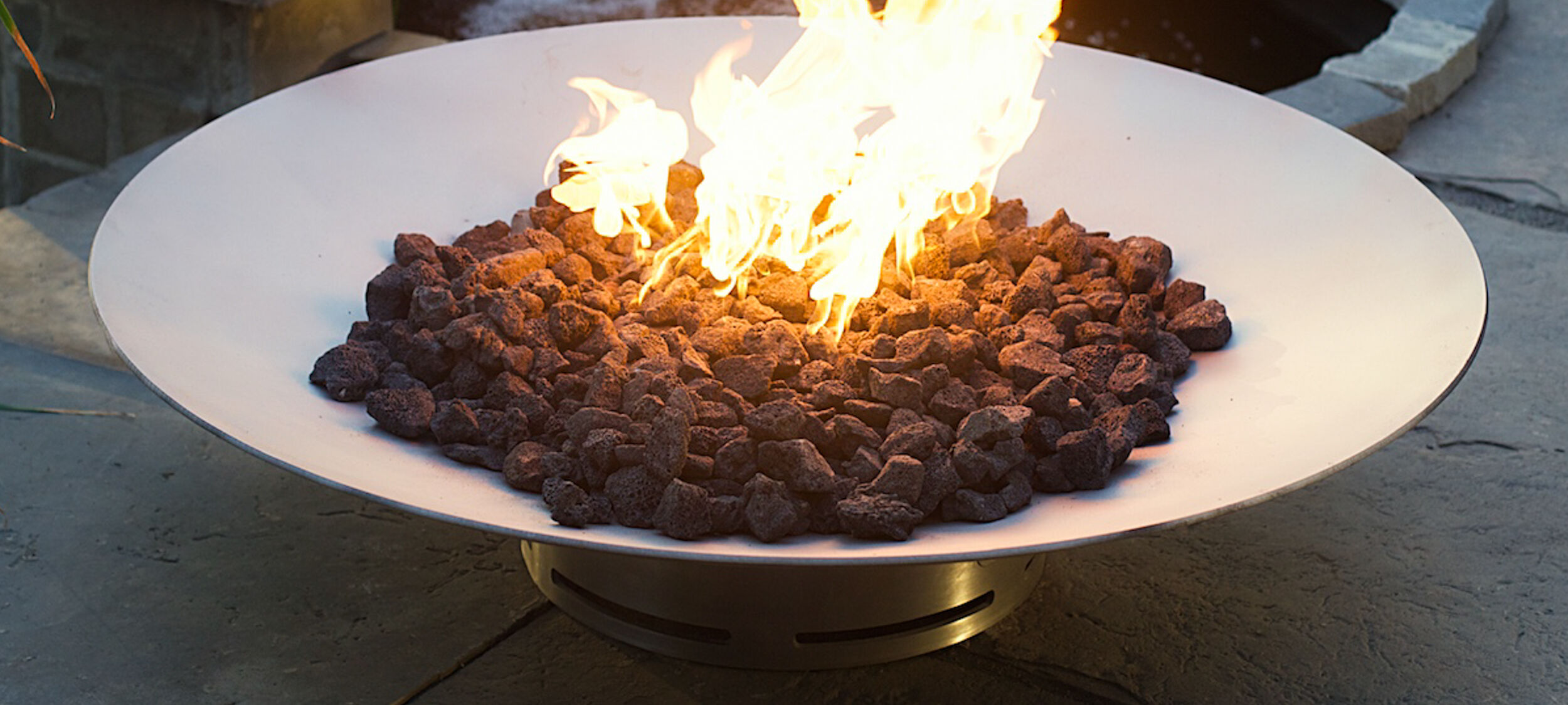 A small, low-profile fire bowl with black lava rock fire media.