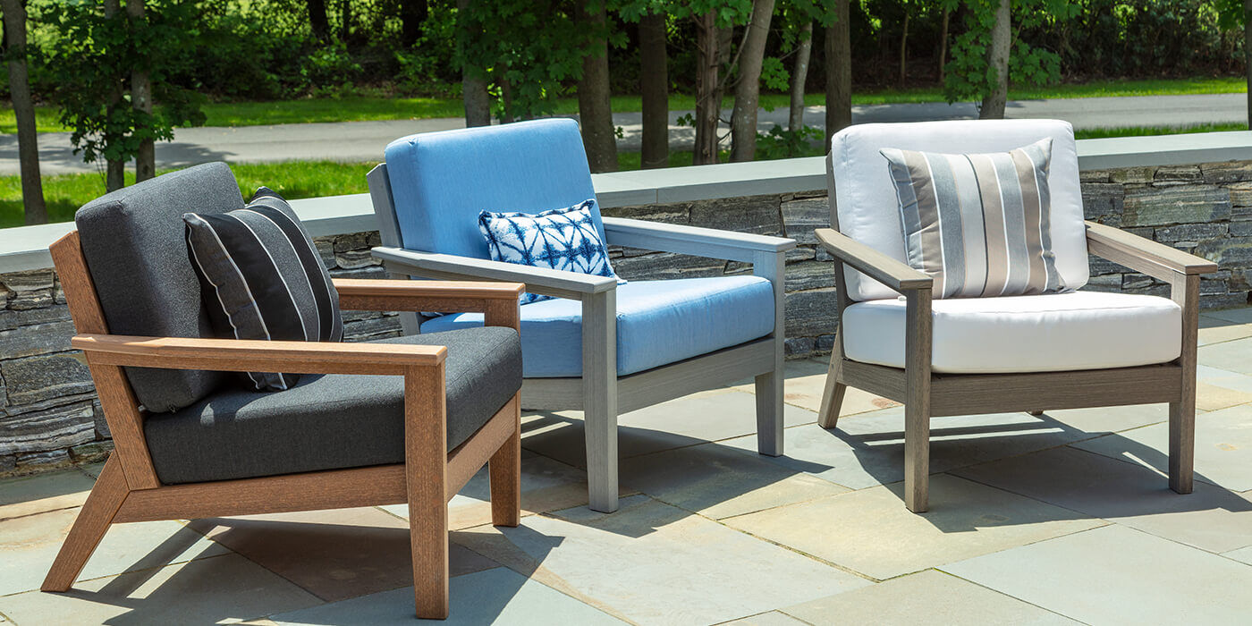 Three outdoor chairs with colorful cushions and pillows.
