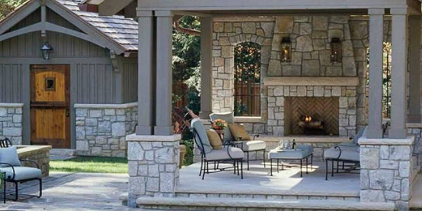Covered outdoor living room with masonry fireplace adjacent to swimming pool
