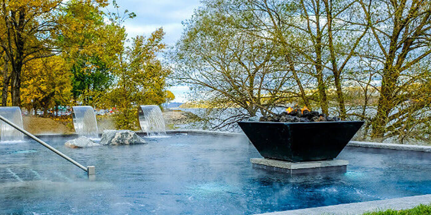 Square black gas fire pit in a vibrant blue pool
