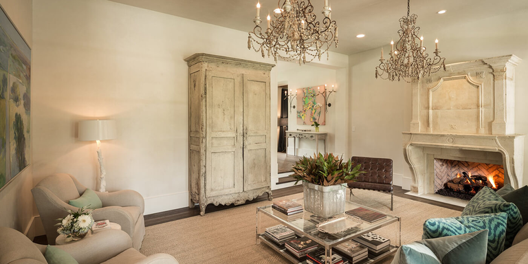 A French Country inspired home with a large, rectangular gas fireplace and intricately carved mantel