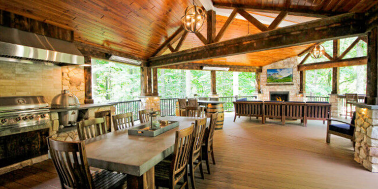 Rustic covered deck with an outdoor kitchen and outdoor living room