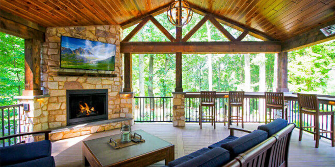 Rustic covered wood deck with outdoor living room and fireplace