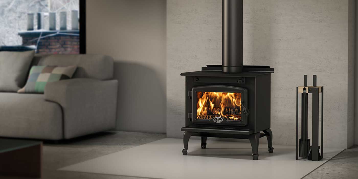 A living room with a classic wood burning stove and some fireplace tools