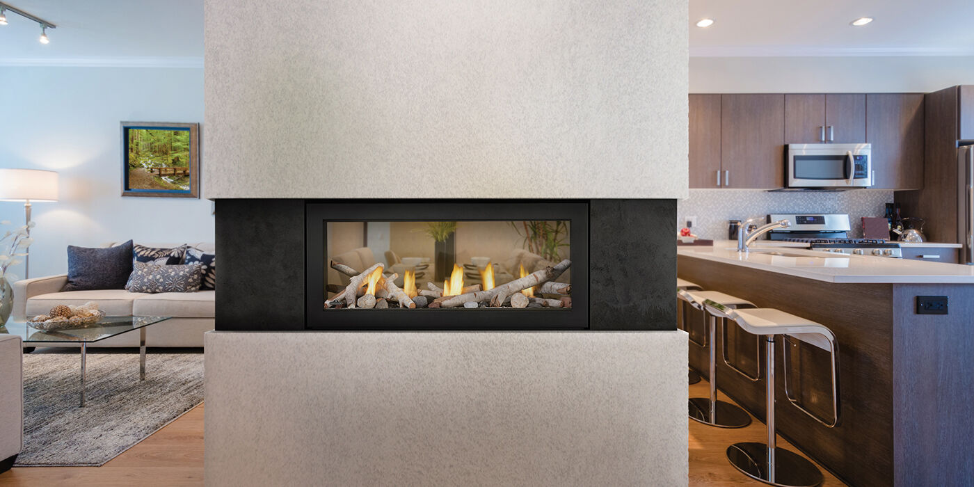A see-through linear gas fireplace installed in a large, open-concept living space with the kitchen on one side and a living room on the other