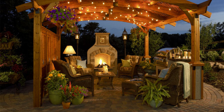 Evening view of backyard patio with gas fireplace and pergola