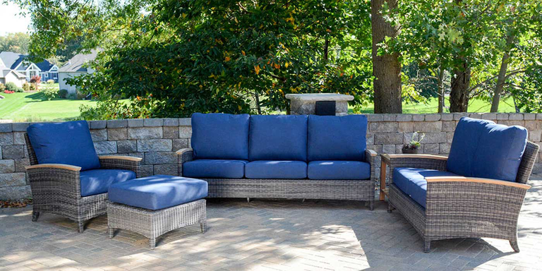 An outdoor patio furniture set with a sofa, two chairs made with resin wicker frames and quick-drying blue foam cushions