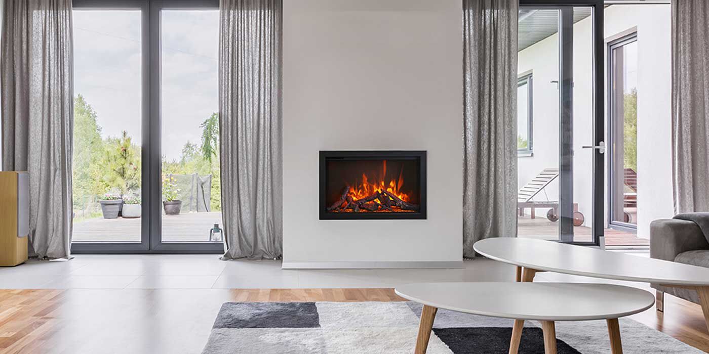 A Mid-Century Modern living space with white walls, floor-to-ceiling windows, airy gray curtains, an oblong oval coffee table, a multi-colored grey and white rug, and a large, rectangular gas fireplace.