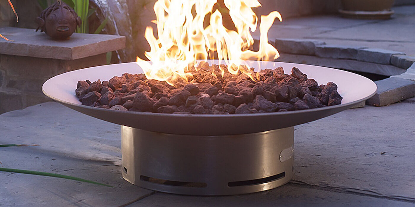 A stainless steel wood burning fire pit set up on an outdoor patio