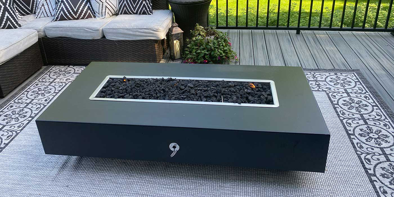 A black, linear gas fire pit with black lava rock media