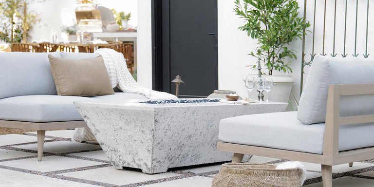 A linear, white gas fire pit installed on a paved outdoor patio