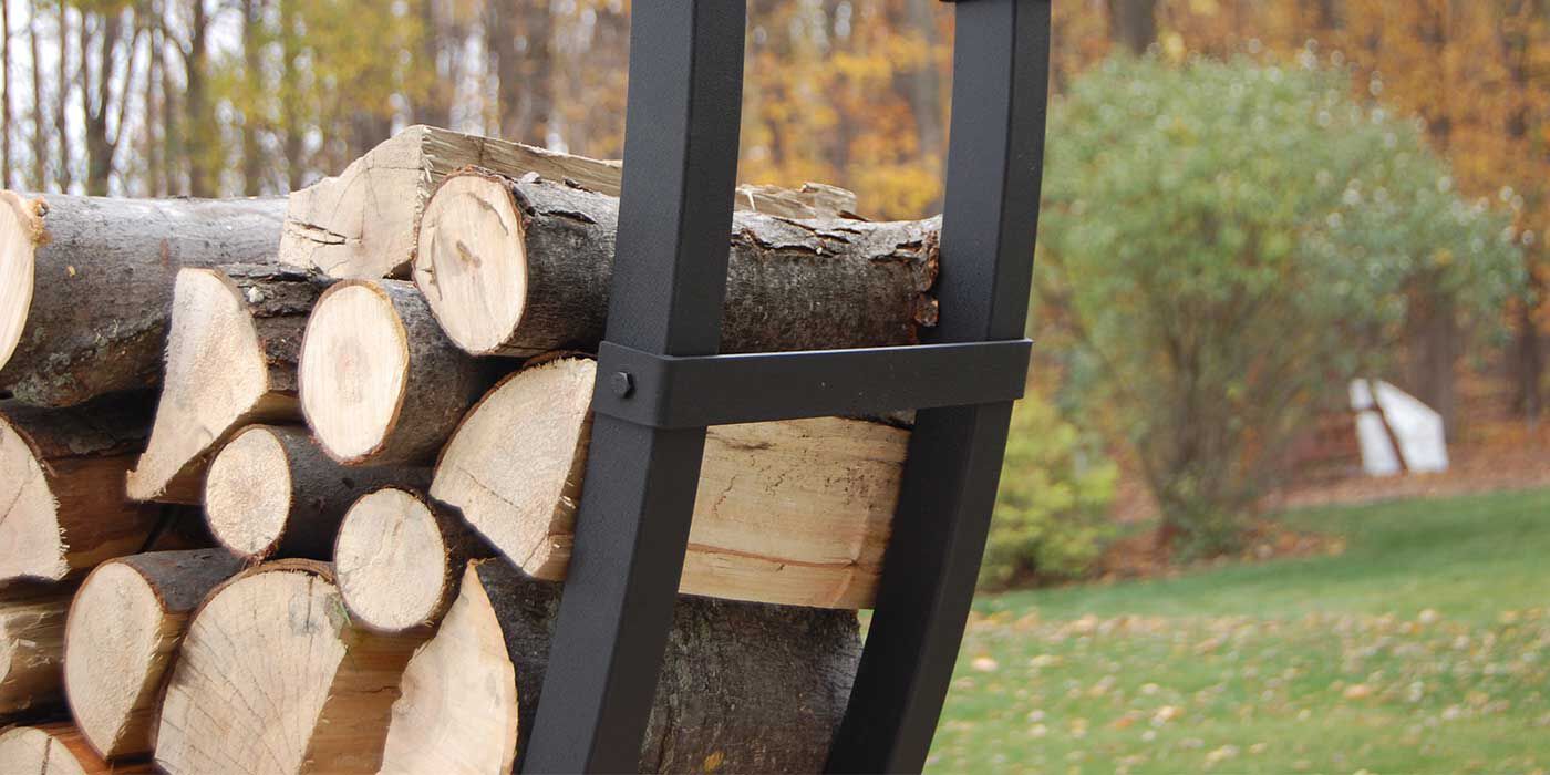 A stack of seasoned firewood on a black firewood rack.