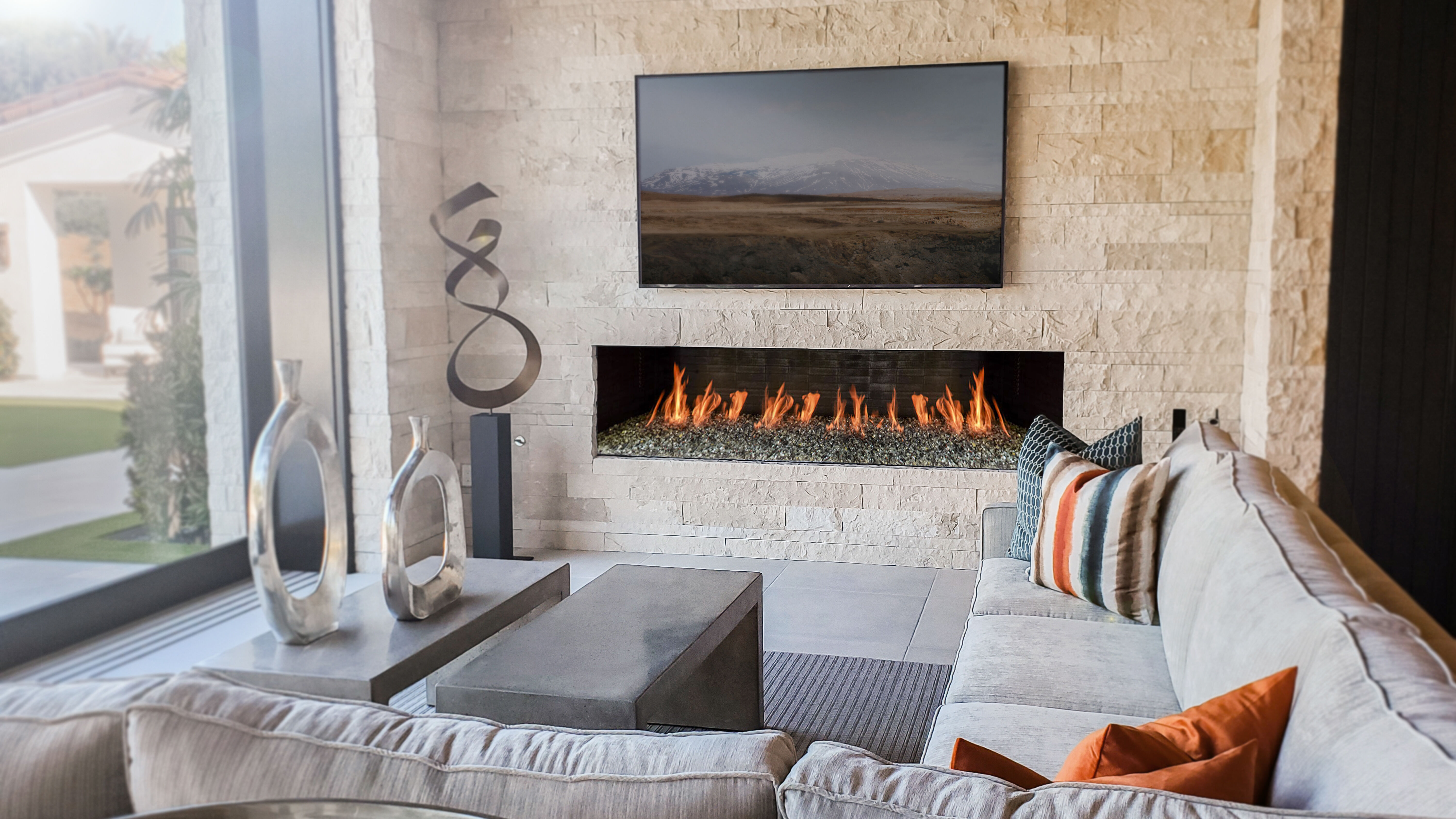 A contemporary living room with a light gray furniture, metal sculptures, and a textured, stone feature wall with a flatscreen TV and a linear gas fireplace.