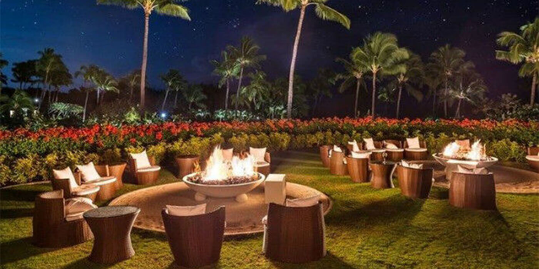 Gas fire pits surrounded by chairs at a Hawaiian resort at night